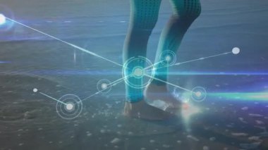 Sahile inen bir kadın performans takibi için spor aletlerini çalıştırıyor. Dijital, teknoloji, refah, fitness, yenilik, açık hava, fütüristik