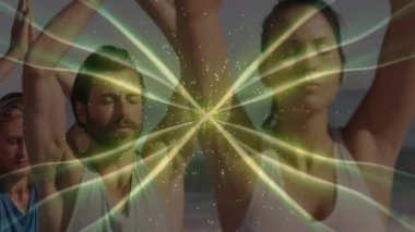 Sahilde kollarını kaldırırken yeşil parlayan enerjiye tepki veren dört yoga uygulayıcısı. Ruhani, ahenk, farkındalık, dinginlik, sağlık, meditasyon, canlılık.