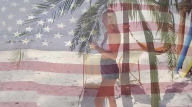 Plajdaki palmiye ağacının altında akıllı telefonu dinleyen bir kadın seyahat fotoğrafçılığı için kare kare çekmek için eğilmiş. Tropikal, boş zaman, rahatlama, doğa, güneşli, açık hava, yaşam tarzı