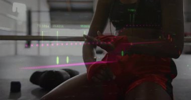 Bir kadın boks ringinde oturmuş, elini sarıp, spor için hazırlanıyor. Sporcu, antrenman, spor, kararlılık, güç, spor