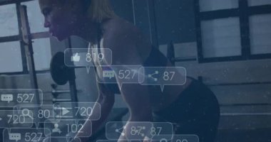 Yetişkin bir kadın spor salonunda dambıl sıralaması yapıyor sosyal medya simgeleri yükseliyor. Fitness, antrenman, güç, motivasyon, dijital, modern, sağlık
