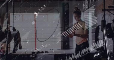 Woman tapping smartwatch showing animated charts as doing cable squat with trainer observing. Fitness, workout, strength, training, industrial, technology, performance