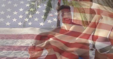 Woman entering frame, joining man and exchanging gestures under waving American flag for travel ad. Beach, tropical, leisure, romance, outdoor, vibrant, relaxation