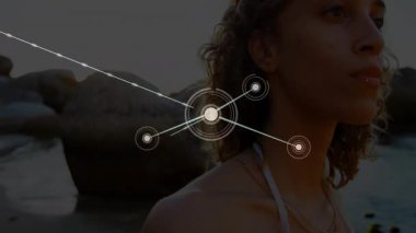 Woman standing at shoreline node appearing at chest initiating technology network growth overlay. Abstract, connectivity, futurism, landscape, serenity, digital, sunset