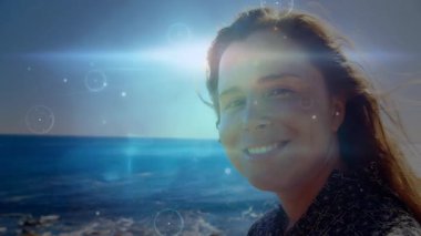 Güneş ışığı objektife çarpıp alevlere ve örtülere yol açarken bir yandan da kadın markalaşmak için başını eğerek gülümsüyor. Deniz manzarası, sükunet, minimalizm, dijital sanat, yaşam tarzı, rahatlama, güzellik