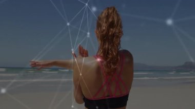 Sağ kolunu kaldıran ve kumsalda omzunu esneten bir kadın animasyon düğümleriyle spor yapıyor. Spor, sağlık, açık hava, modern, sağlık, egzersiz, yaşam tarzı