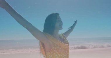 Sağlık oturumunda kumlu sahilde deniz esintisini kucaklayan kollarını kaldırıp hava soluyan bir kadın. Özgürlük, huzur, farkındalık, açık hava, huzur, rahatlama, mutluluk.