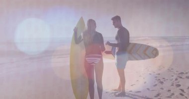 Erkek ve dişi sörfçüler sörf yapmaya başlamadan önce sörf tahtalarıyla beşlik çakıyorlar. Macera, yoldaşlık, spor, açık hava, yaşam tarzı, eğlence, enerjik