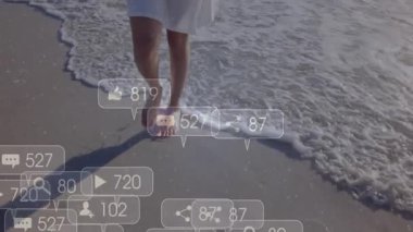 Güneşli plajda yürüyen bir kadın canlı sosyal medya ikonlarına sebep oluyor. Güncelleme her adımda sayılıyor. Sahil şeridi, dinginlik, doğa, dijital, etkileşim, sükunet, minimalizm