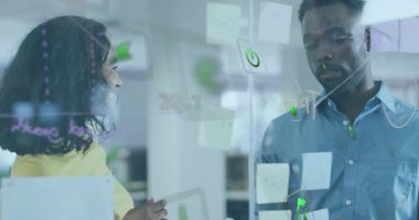 Kadın yapışkan notlara işaret ediyor, iş planlaması için tablet seçiyor, erkek işaretleyici notlar yazıyor. İşbirliği, beyin fırtınası, yenilik, takım çalışması, strateji, modernlik, yaratıcı süreç