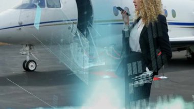 İş jetinin yanındaki akıllı telefona konuşan ve uçuş verileriyle holografik grafikleri aktive eden bir kadın. Lüks, yenilik, teknoloji, kurumsal, fütüristik, iletişim, zarafet