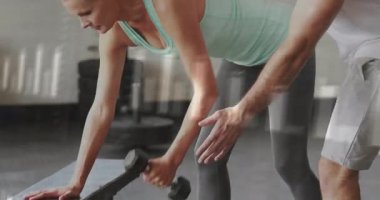 Kadın halteri kavrayıp kürek çekerken fitness eğitmeni duruşunu ve kuvvet gösteren grafikleri gösteriyor. Kuvvet, eğitim, denetim, biyomekanik, ilerleme, spor, fitness