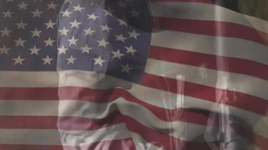 Bayrak örtüsü, erkek operatörün tüfeği kaldırdığını ve savunma eğitimi için dürbünü hizaladığını gösteriyor. Vatanseverlik, güvenlik, hazırlık, disiplin, taktik, savunma, militarizm