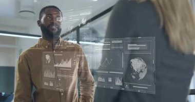 İş arkadaşları hologram haritasına bakıyorlar sonra da eğilimleri gösteren çizelgeye işaret ediyorlar. Teknoloji, yenilik, işbirliği, veri görselleştirme, fütüristik, girişim, analitik