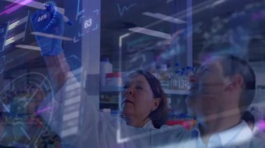 Kadın bilim adamı cam projeksiyonları üzerine işaret kaldırıyor ve veri analizi için ölçümleri daire içine alıyor. Araştırma, işbirliği, yenilik, teknoloji, analitik, profesyonel, modern