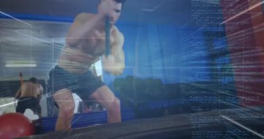 Balyozu kavrayan adam jimnastik salonunda dijital izleme performansıyla lastikleri parçalıyor. Güç, zindelik, eğitim, dijital, egzersiz, kas gücü, dayanıklılık