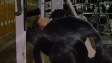 Fitness meraklısı halteri kaldırıyor, göğüs gücü için eğimli bankı indiriyor ve bastırıyor. Dayanıklılık eğitimi, spor ortamı, kas fiziği, ağırlık kaldırma, egzersiz seansı, fitness ekipmanları, atletizm eğitimi