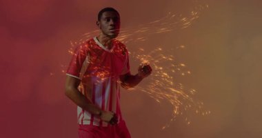 Futbolcu gradyan stüdyoda kayıyor, altın kıvılcımlar kıvrılıyor ve topa vurarak gücünü gösteriyor. Atletik, hareketli, enerjik, dinamik, spor, dijital, canlı