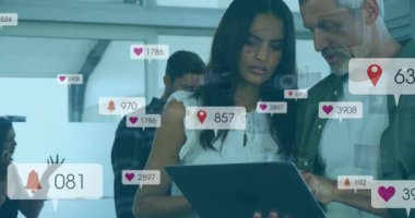 Kadın ve erkek teknoloji ofisinde tablet tıkırdatıyor yüzen raptiyelerle, kalplerle, zillerle ölçümleri takip ediyorlar. İşbirliği, analitik, veri, teknoloji, takım çalışması, yenilik, dijital