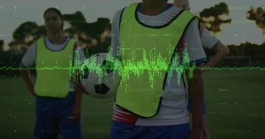 Spor performansı için orta sahada futbol topunu tutarken, yeşil dalga formunu gösteriyor. Atletizm, takım çalışması, açık hava, canlı, kararlılık, fitness, rekabet