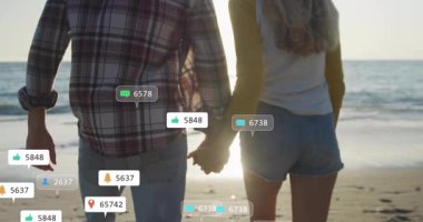 Sahilde gezinen bir çift, yükselen sosyal medya ikonlarına ve koşuya cevap veriyor. Romantik, boş, dijital, canlı, açık hava, bağlantı, enerjik