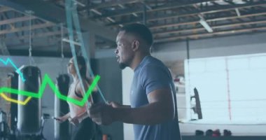 Egzersiz ikilisi spor salonunda atlama halatına başlarken renkli çizelgeler de yoğunluğu yansıtıyor. Fitness, training, cardio, motivasyon, sağlık, egzersiz, dayanıklılık