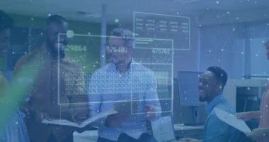 Elinde klasör tutan orta yaşlı bir adam ve ofisteki dijital finans tablolarının güncellenmesine işaret eden iş arkadaşları. İşbirliği, takım çalışması, veri analizi, dijital görseller, profesyonel, iş dünyası, modern