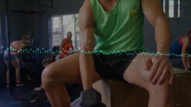 Yeşil, üst kıvrımlı halterli bir erkek kaldırıcıların arasında spor salonunda güç gösterisi yapıyor. Fitness, dayanıklılık, halter, antrenman, spor salonu, kas gücü.