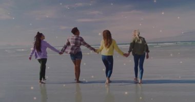 Arkadaşlar kumsalda el ele yürür, zıplar, parlaklıklara yol açar ve refahı ön plana çıkarırlar. Kıyı şeridi, yoldaşlık, sükunet, doğal, tasasız, birlik, yaşam tarzı.