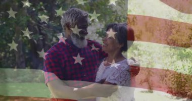 Yarı şeffaf Amerikan bayrağı dolgu çerçevesini kaplarken çiftler pazarlama için bahçede kucaklaşıyorlar. Romantizm, sevgi, vatanseverlik, açık hava, sükunet, kutlama, mutluluk