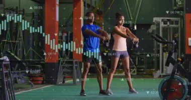 Fitness partnerleri çimenlikte kettlebell kavrıyor ve veri grafikleri ile kalçalarını sallıyor. Eğitim, güç, egzersiz, spor, spor, güç, dayanıklılık.