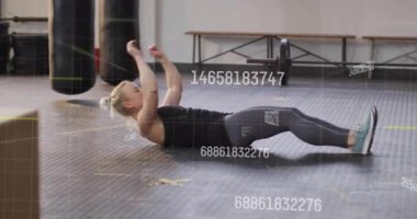 Orta yaşlı bir kadın karın kasları kasıyor spor salonundaki plastik paspasa kıvrılıp çekirdek kontrolünü gösteriyor. Spor, güç, egzersiz, sağlık, tonlama, atletik