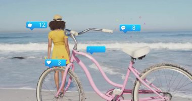 Bisikletin üzerinde kabarcıklar yükseliyor, sarı elbiseli kadın ayakta duran sosyal ikonlar alıyor. Yaz, eğlence, dijital bağlılık, açık hava, sükunet, kutlama, gündelik