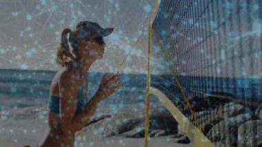 Kadın ağlara doğru yürüyor ve sarı ipi tutuyor. Plaj voleybolunda hazır durduğunu varsayıyor. Atletik, boş zaman, açık hava, spor, rahatlama, rekabetçi, enerjik