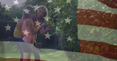 Bahçıvanlık eğitimi veren anne ve kızı çalılara doğru yürürken bayrak böğürtlen toplamada rehberlik ediyor. Aile, yetiştirme, açık hava, canlı, neşeli, doğal, bağ kurma