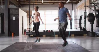 Erkek ve kadın halatları sıkıyor, hareketli çizelgeleri salonda takip ederek senkronize zıplamayı başlatıyorlar. Fitness, cardio, training, dynamic, energy, wellness, modern