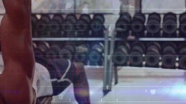 Spor salonunda dambıllara basan adam asansörü grafiklerle çalıştırıyor, kod izleme performansı. Kuvvet eğitimi, fitness, dijital analiz, atletik, egzersiz, biyomekanik, performans