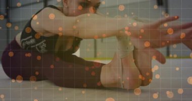 Teen gymnast folding forward lifting arms overhead in gym wearing grip socks warming up for fitness. Flexibility, athleticism, training, wellness, movement, sportswear, minimalist