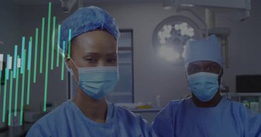 Ameliyathanede iki cerrah var, sol kenarlarından yeşil çubuklar yükseliyor, monitör örtüsü örüyor. Tıbbi, takım çalışması, yenilik, teknoloji, sağlık, hassasiyet, profesyonellik