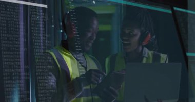 Veri merkezinde tableti tıklatan ve dizüstü bilgisayarda yazan teknisyenler doğrulama sonuçlarını gösteren kodlar gösteriyorlar. Teknoloji, siber güvenlik, işbirliği, yenilik, modern, endüstriyel, analitik