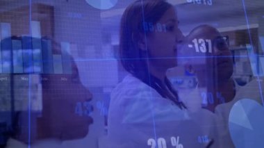 Saydam ekran grafiklerine dokunan baş araştırmacı veri eğilimlerini izlemek için rakamları canlandırıyor. Analizler, yenilik, işbirliği, teknoloji, bilim, laboratuvar, veri görselleştirme