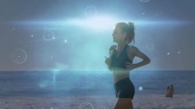 Female runner jogging past couple while fitness AR activating rings as light rises above waves. Athleticism, digitalart, seaside, wellness, serenity, motion, innovation
