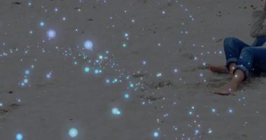 Woman noticing glowing sparkles and sitting on beach, man joining and embracing for marketing. Romantic, intimacy, serenity, leisure, tranquility, minimalist, outdoor