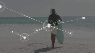 Sörf tahtasıyla okyanusa yürüyen sörfçü suya giriyor teknolojiyi başlatıyor harita verilerini örtüyor. Plaj, okyanus, dalgalar, kıyı şeridi, sörf, macera, teknoloji