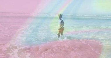 Çocuk sörf yapmak için deniz köpüğü içinde yürürken dalga grafiğini aktifleştiriyor. Eğlence, el sallama, su sıçratma, plaj, yaz, canlı, macera