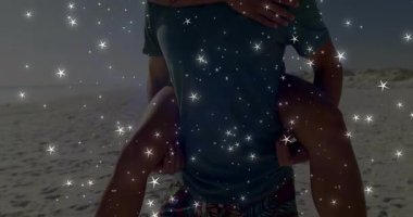 Erkek kıyıda yürümeye başlar, kadını sırtında taşır kadın şen şakrak seyahat sahnesine hasır şapka takar. Sahil, çift, boş zaman, güneş ışığı, günlük giysi, sahil, mutluluk.