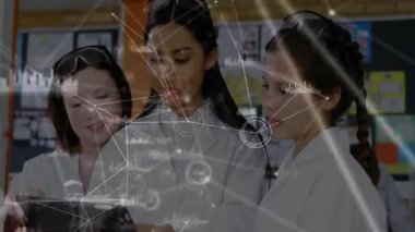 Üç öğrenci tablet ekranı tıklatıyor ve grup bilim projesi için animasyon veri grafiklerini inceliyor. İşbirliği, eğitim, yenilik, teknoloji, veri görselleştirme, kök, gençlik