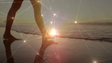 Çıplak ayaklı kadın kıyı şeridine adım atıyor ve teknolojik görüntüler için ışıldayan ağı etkinleştiriyor. Deniz manzarası, sükunet, dijital, bağlantı, gündoğumu, yansıma, dinginlik