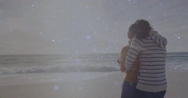 Gün doğumunda kumsalda kucaklaşan çift, parlak parçacıklar sürükleniyor teknik demo için rüya gibi parlıyor. Romantik, sükunet, sükunet, siluet, ahenk, ahenk, minimalist