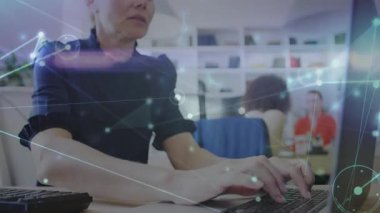 Ofiste veri akışını görselleştiren animasyon ağ grafiklerini başlatan tuş vuruşları yazan olgun bir kadın. Profesyonel, bağlantı, dijital, işbirliği, üretkenlik, modern, çalışma alanı